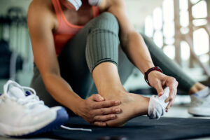 close up of athletic woman injured her foot during workout at th
